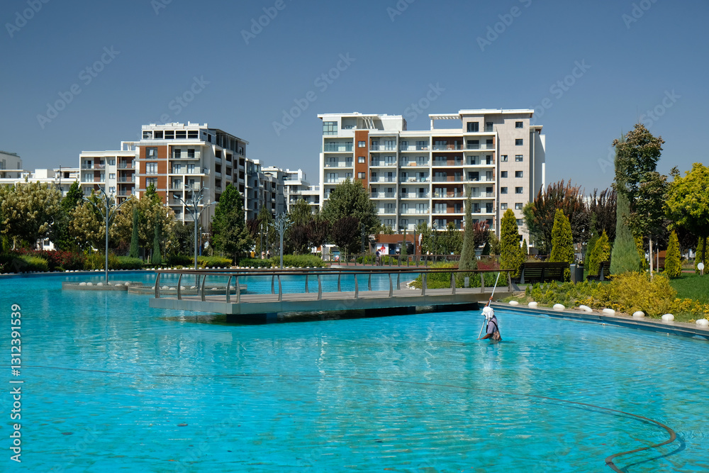 Fototapeta premium artificial pond with blue water in the park and buildings in the background, Tashkent