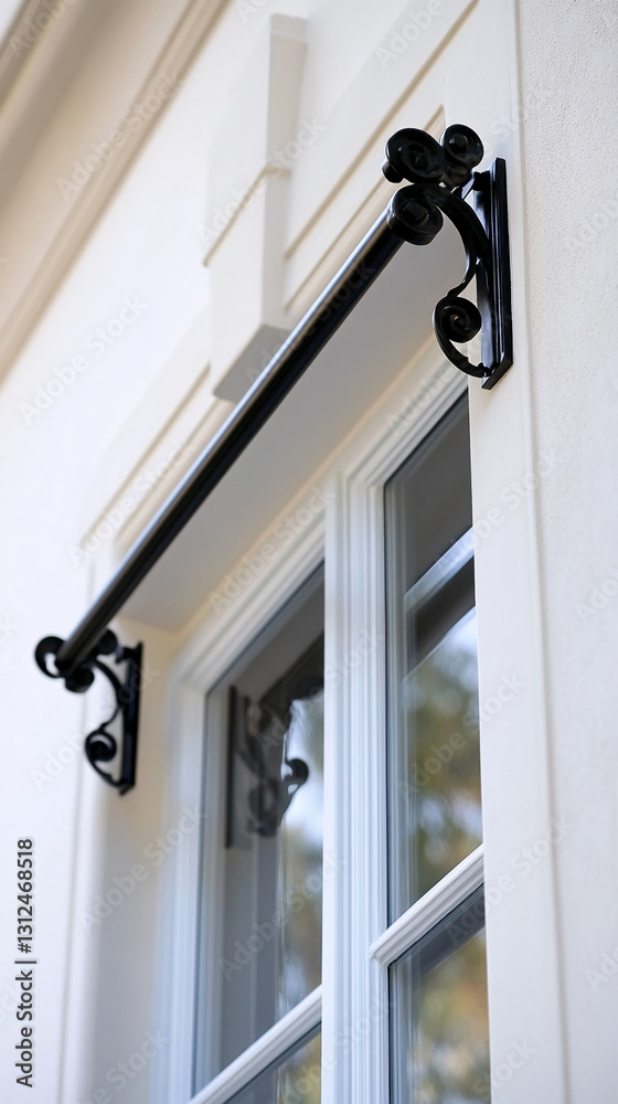 Close-up of black metal window awning bracket, showcasing intricate scrollwork against white wall, suggesting elegance and architectural detail Close-up of black metal window awning bracket, showcasing intricate scrollwork against white wall, suggesting elegance and architectural detail