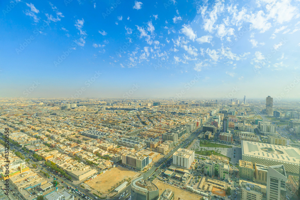 Fototapeta premium Panoramic view of Riyadh, the capital city of Saudi Arabia, showcasing its vast urban sprawl, modern architecture, and bustling streets under a clear blue sky with scattered clouds
