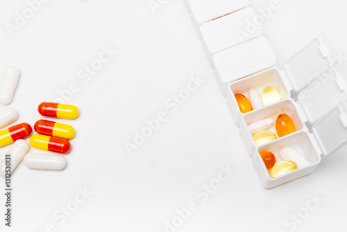  pillbox by days of the week with fish oil and various pills, on a white background. pillbox for keeping up with your vitamin regimen