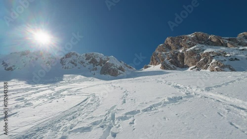 Snowy Alpine Ascent Under the Sun in the Italian Mountains. A pristine winter landscape in the Italian mountains, featuring a steep snow-covered slope leading up to rugged rocky peaks.