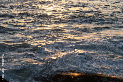 Golden sunset glimmering over wavy seascape, foaming waters near bari sardo in ogliastra, sardinian coastline, italy