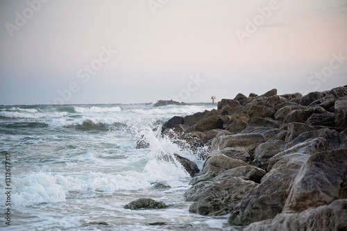 Ocean waves crashing against rocky shoreline under an overcast sky