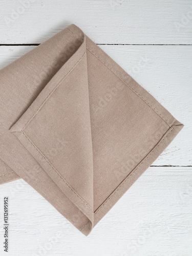 Beige napkin on a wooden white background. Closeup.