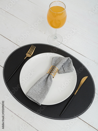 Grey napkin on a white plate. Serving on wooden table.