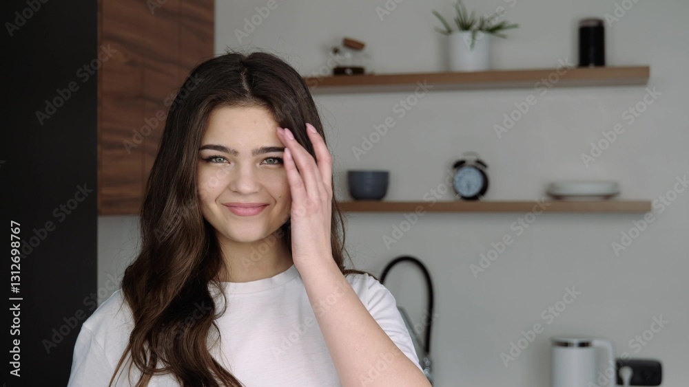 Young woman in kitchen during quarantine. Posing on camera with smile. Touching face and chin with hand. Sexy girl with natural beauty. Young woman in kitchen during quarantine. Posing on camera with smile. Touching face and chin with hand. Sexy girl with natural beauty.