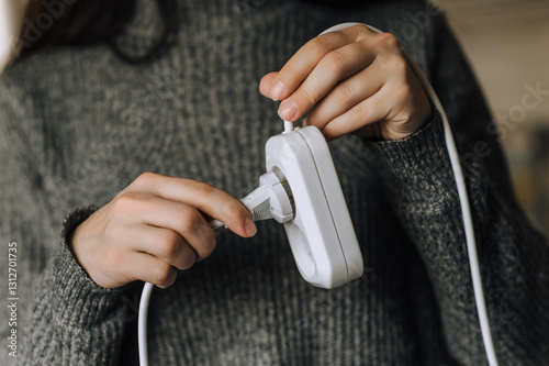 Woman inserting white plug into extension cord socket with her hands to turn on electricity. Photo, technology concept. photo