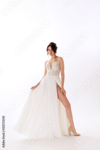 Elegant bride in white gown showcasing silhouette adorned with intricate details in a minimalist studio setting