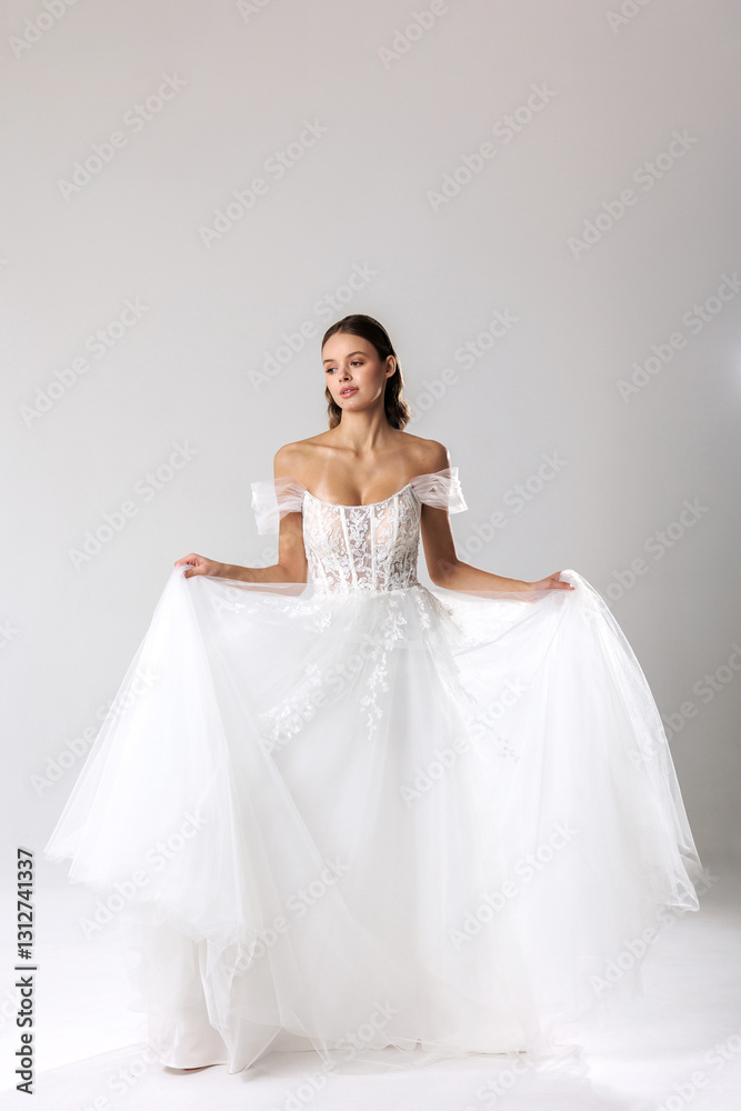 Elegant woman wearing a beautiful white gown poses gracefully in a studio setting Elegant woman wearing a beautiful white gown poses gracefully in a studio setting