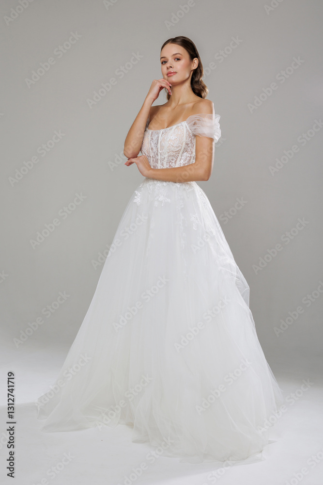 Elegant bride showcases stunning white wedding dress with intricate details in neutral studio setting Elegant bride showcases stunning white wedding dress with intricate details in neutral studio setting
