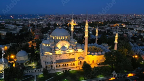 Aerial view of the illuminated Süleymaniye Mosque in Istanbul at night, with the cityscape and Aqueduct of Valens in the background, highlighting its historical and cultural significance
