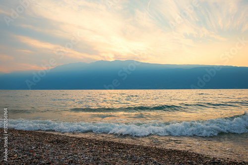 Fototapeta Naklejka Na Ścianę i Meble -  rolling waves on the beach of Gargnano Lake Garda, dreamy sunset scenery, italy