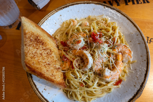 Cuadro en lienzo Top-down view of shrimp scampi pasta with a side of garlic bread on a rustic woo