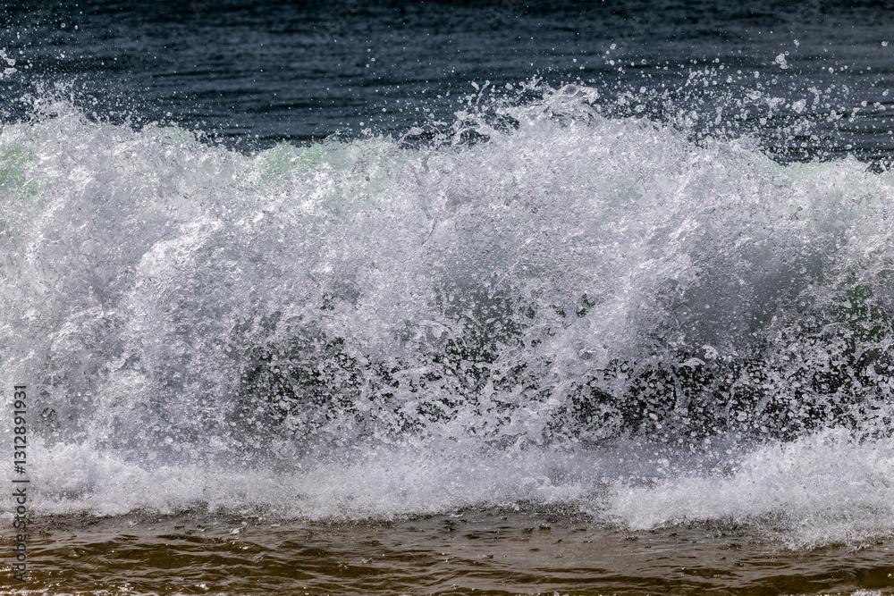 Frozen wave breaking on to sandy beach Frozen wave breaking on to sandy beach