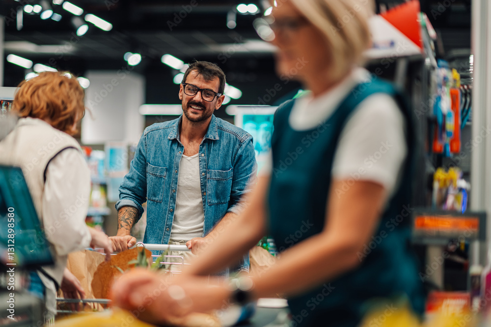 Obraz premium Smiling customer pushing shopping cart at checkout in supermarket