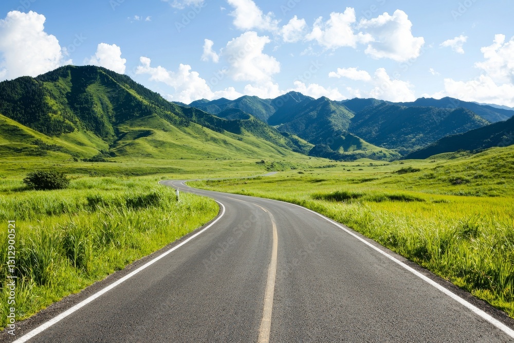 Fototapeta premium A rural road winds through lush green grass set against a stunning mountain backdrop under a brilliant blue sky
