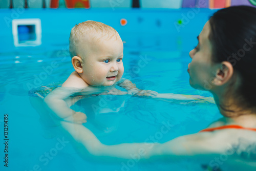 Obraz na płótnie Swimming lessons for children in the pool. A baby swims in the pool with a female coach. w salonie