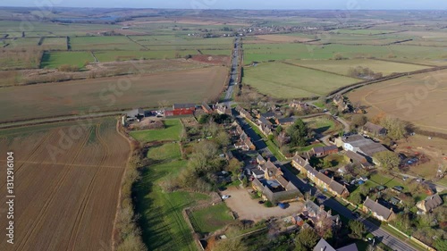Explore the English Countryside East Midlands aerial drone views of a quaint village with traffic passing through on a sunny day. photo