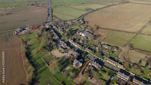 Explore the English Countryside East Midlands aerial drone views of a quaint village with traffic passing through on a sunny day. photo