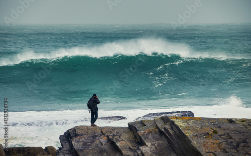 Photographer taking a picture of a large incoming wave