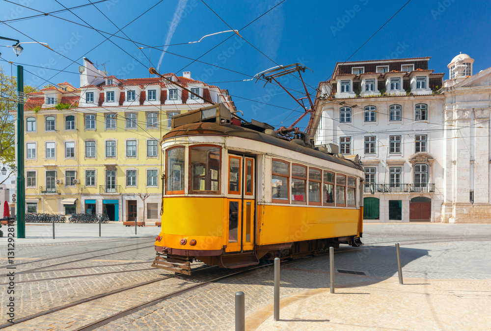 Classic yellow tram in Lisbon, Portugal, in a historic square with traditional Portuguese buildings under a clear blue sky