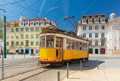 Obraz na płótnie Classic yellow tram in Lisbon, Portugal, in a historic square with traditional Portuguese buildings under a clear blue sky w salonie