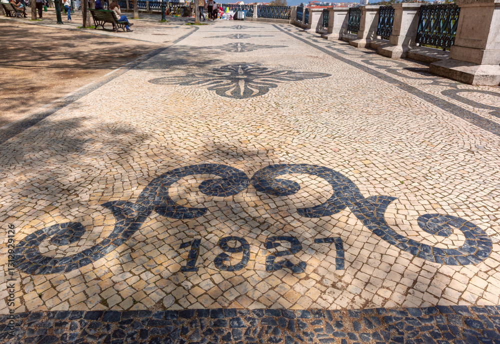 Decorative Portuguese pavement with black and white stone patterns carved on the Miradouro de Santa Catarina in Lisbon, Portugal