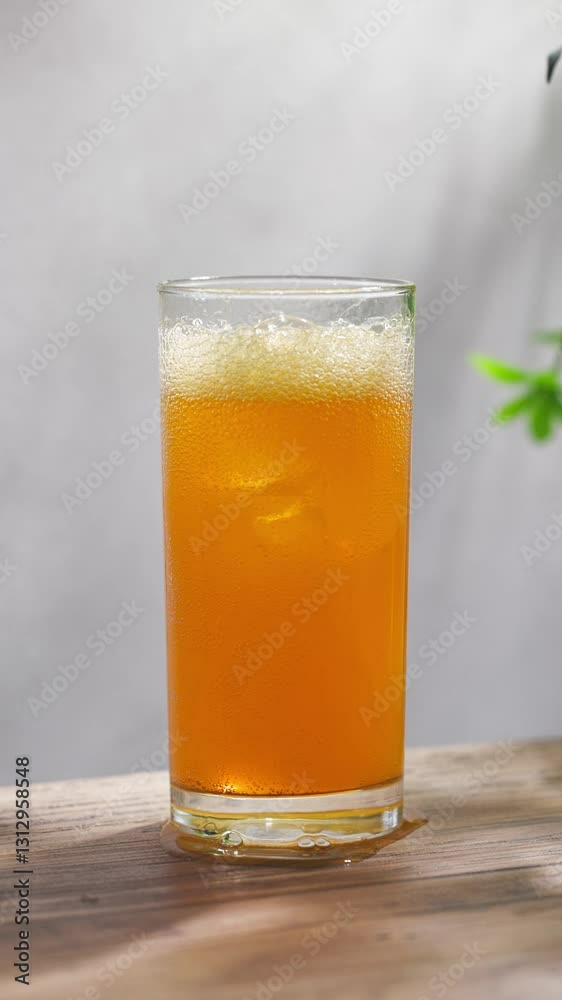 fresh sparkling orange juice drink in a glass on sunny wooden kitchen tabletop and gray wall background, slow motion fresh sparkling orange juice drink in a glass on sunny wooden kitchen tabletop and gray wall background, slow motion