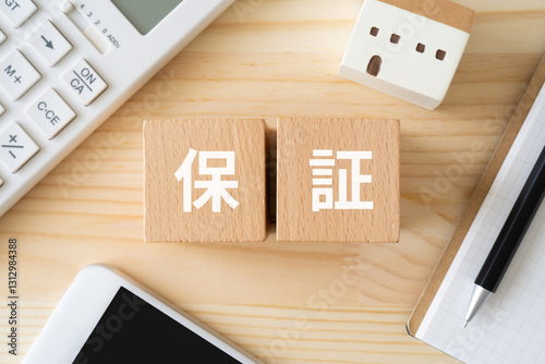 保証と書かれたブロック、電卓、家のおもちゃ