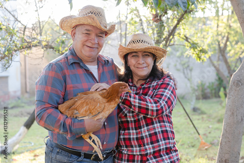 Elderly Latin American Couple with a chicken from their farm - Grandparents couple with farm animals