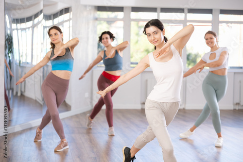 Enthusiastic young woman energetically participating group choreography class, learning modern dynamic dances..