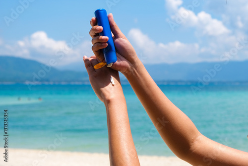 Hand of female holding sunscreen. Very sun light Sky background.Health concepts and skin care	