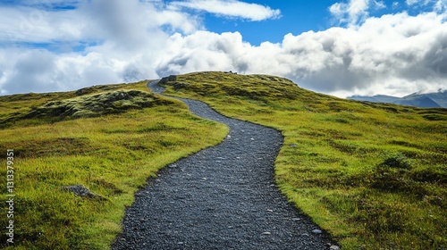 A winding gravel path leads through lush green hills under a bright blue sky adorned with fluffy clouds.