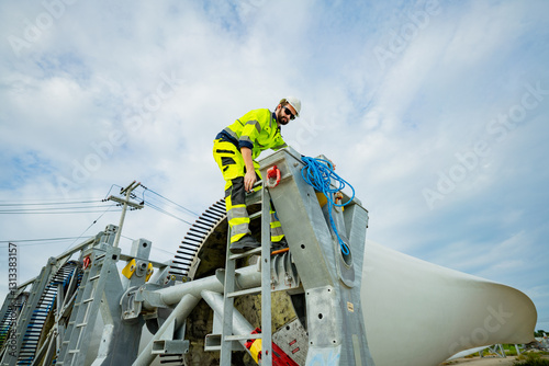 Worker climbs structure during wind turbine installation at construction site in daylight