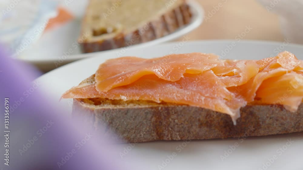 Slices of Scottish Smoked Salmon Carefully Placed on Sourdough Bread by Female Hands for Healthy Morning Breakfast Slices of Scottish Smoked Salmon Carefully Placed on Sourdough Bread by Female Hands for Healthy Morning Breakfast