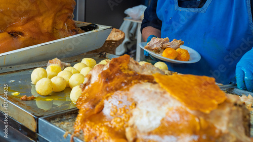 Konstfotografi Traditional Ecuadorian roasted pork with crispy skin, served with potatoes and mote at a street food market