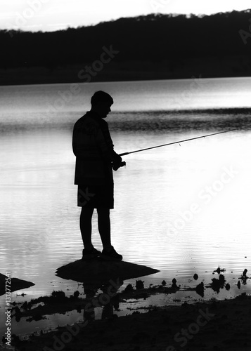 Sillhouette of Boy fishing at sunset