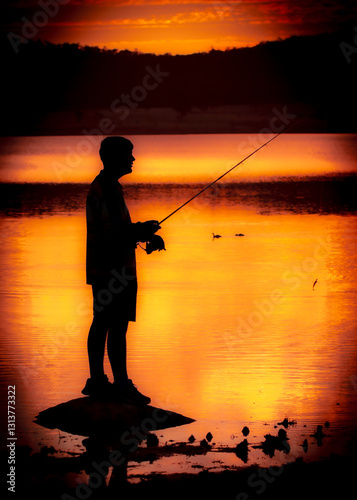 Sillhouette of Boy fishing at sunset