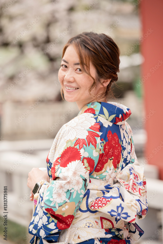 Fototapeta premium Woman in a colorful floral kimono smiles warmly while looking back