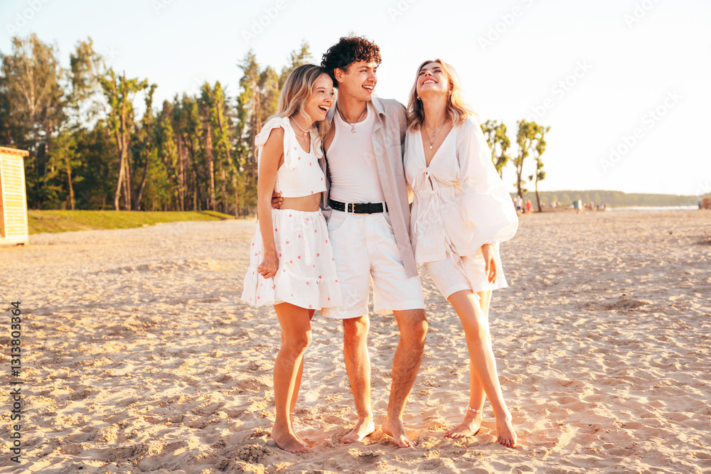 Group of young smiling friends having fun at the seaside. Man and two cute female at sunset in casual summer clothes. Young women hugging his friend at sunrise. Enjoy their life, at the beach Group of young smiling friends having fun at the seaside. Man and two cute female at sunset in casual summer clothes. Young women hugging his friend at sunrise. Enjoy their life, at the beach