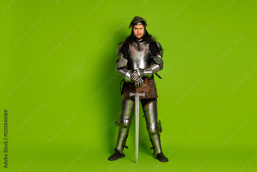 Young male knight in medieval armor posing heroically against a vivid green background, portraying medieval warrior bravery Young male knight in medieval armor posing heroically against a vivid green background, portraying medieval warrior bravery