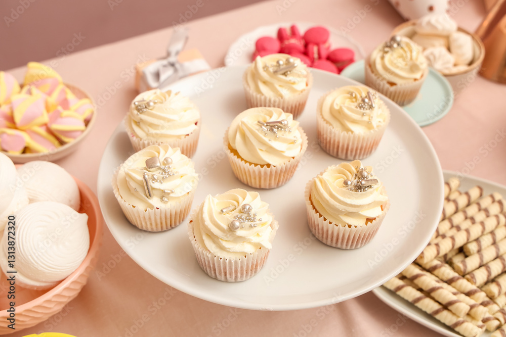 Dessert stand with tasty white cupcakes and other sweets for birthday party on table Dessert stand with tasty white cupcakes and other sweets for birthday party on table