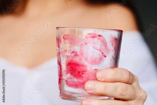 close up of a woman's hand holding a glass with traces of a kiss