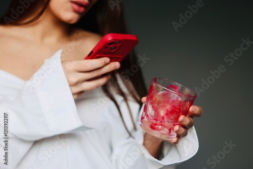 Young woman in white taking a picture of a glass with lipstick kiss marks. Concept Valentine's Day celebration 