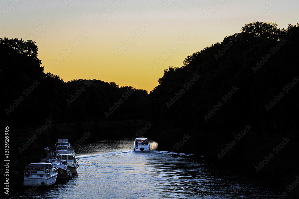 Fototapeta premium Boat cruising on a calm canal during sunset