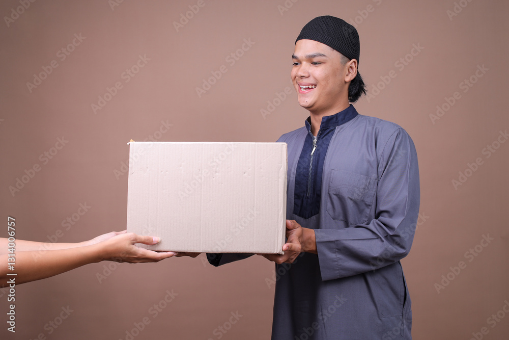 Young Muslim Guy Giving Package Box While Hand Receive It Celebrating Eid On Beige Background