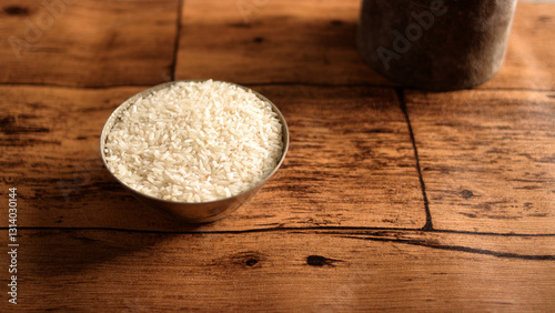 Metal bowl filled with uncooked white rice on a rustic wooden surface, representing Zakat Fitrah, the obligatory charitable donation during Ramadan
