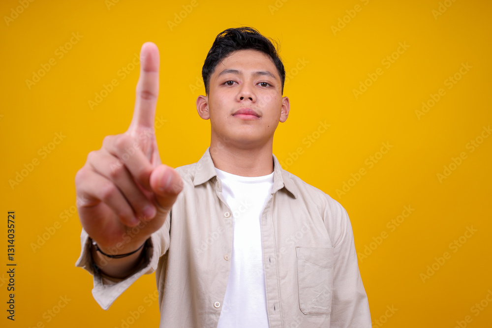 Asian Young Man Showing No Gesture With Finger Up Isolated on Yellow Background