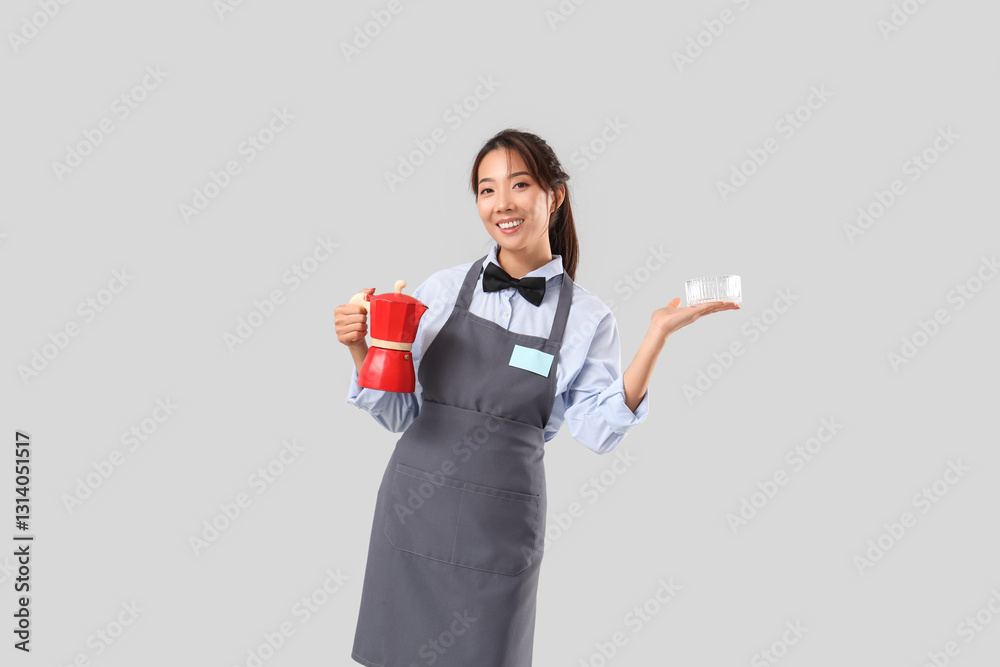 Young Asian smiling waitress with coffee pot and ashtray on grey background