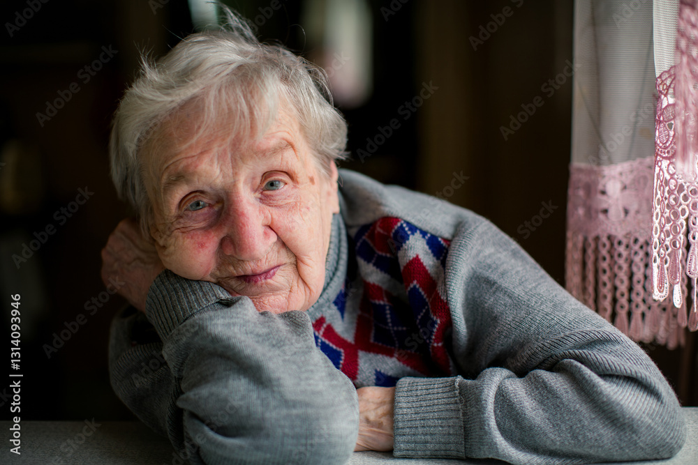 A soulful close-up portrait of an elderly woman posing while seated at a table, capturing her wisdom and quiet strength.